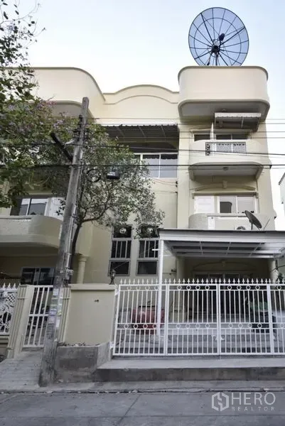Townhouse for rent in Wang Thonglang, Bangkok - Three-storey townhouse exterior with balconies, gated carport and satellite dish in Bangkok.