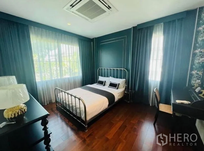 บ้าน ให้เช่าหรือขายในWatthana, Bangkok - ห้องนอนโทนสีเขียวเข้ม เตียงโครงโลหะ และพื้นไม้