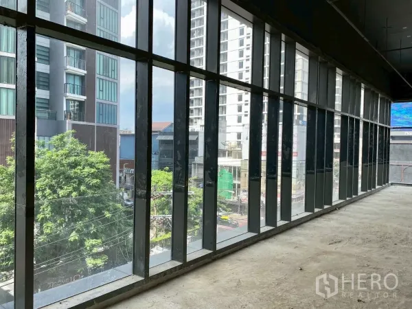 Retail Space for rent - Long wall of full-height windows overlooking trees and high-rise buildings.