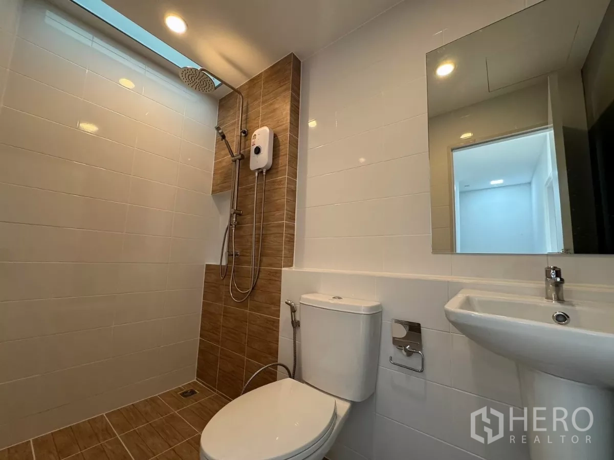 Townhouse for rent in Bang Phli, Samut Prakan - Bathroom with walk-in shower, toilet, and pedestal sink under skylight
