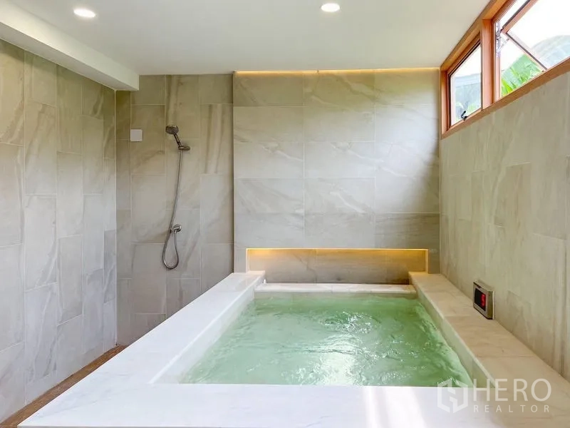 Townhouse for rent or sale - Onsen-style indoor soaking tub with LED lighting and handheld shower in a stone-tiled bathroom.
