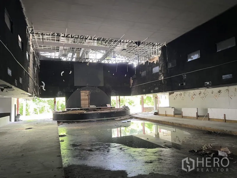 Warehouse for rent in Bang Kapi, Bangkok - Wide high-ceiling hall with exposed grid and reflective floor puddle offering open space.