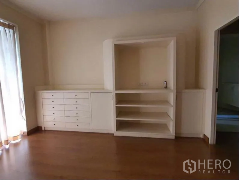 Townhouse for rent in Huai Khwang, Bangkok - Bedroom built-in cabinetry with drawers and open shelving on wood flooring.