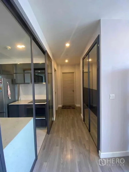 Condominium for rent or sale in Bang Rak, Bangkok - Hallway with sliding glass partitions and wood flooring leading to bedrooms.