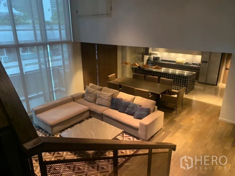 公寓 出租在Watthana, Bangkok - 夹层视角，客餐区与瓷砖中岛厨房，配铜色吊灯。