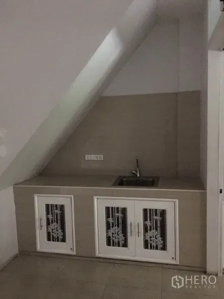 Shophouse for rent in Khlong Toei, Bangkok - Compact under-stair kitchenette with sink and storage cabinets.
