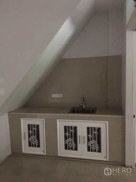 Shophouse for rent in Khlong Toei, Bangkok - Compact under-stair kitchenette with sink and storage cabinets.