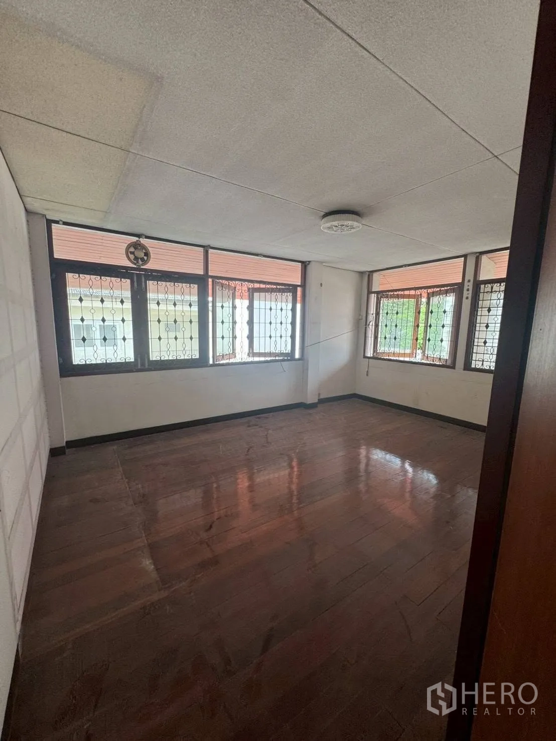 独栋房屋 for rent or sale in Watthana, Bangkok - 楼上房间，木地板与带铁艺的窗户。