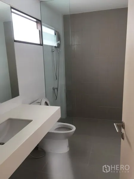 Townhouse for rent or sale in Saphan Sung, Bangkok - Modern bathroom with glass shower enclosure, wide vanity and toilet in neutral tones.