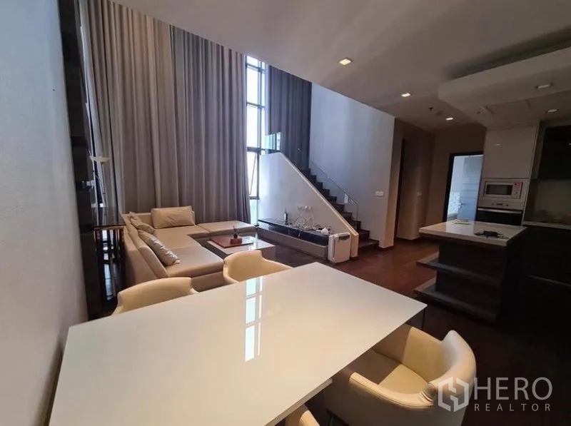 公寓 出租或出售在Huai Khwang, Bangkok - 餐桌面向客厅与楼梯，大窗引入充足自然光。