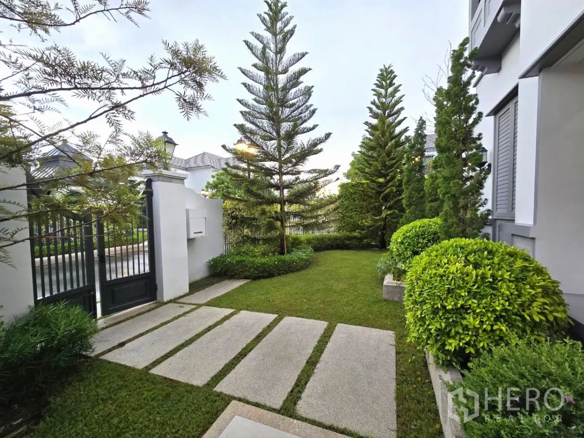 独立式住宅 出租在Saphan Sung, Bangkok - 私家庭院，踏步石小径、常青树与黑色铁门。