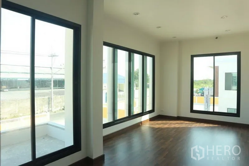 Factory for sale in Bang Pakong, Chachoengsao - Bright corner office with floor-to-ceiling windows and wood flooring.