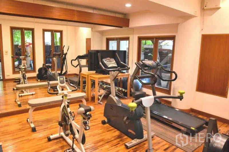 Apartment for rent in Sathon, Bangkok - Fitness room with treadmills, exercise bikes and a mirrored wall.