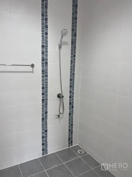 Home Office for sale in Lat Krabang, Bangkok - Walk-in shower area tiled in white with vertical blue mosaic strips and handheld shower.