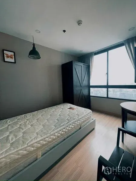 Condominium for rent in Suan Luang, Bangkok - Bright bedroom with single bed, wardrobe, desk, and city view window