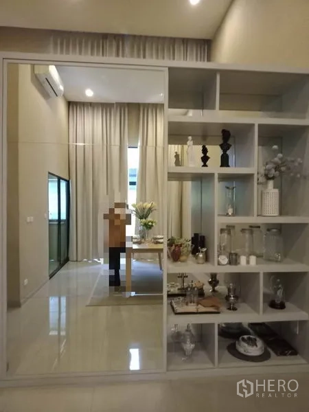 Townhouse for rent or sale in Suan Luang, Bangkok - Built-in display shelves with a sliding mirrored panel reflecting the dining space.