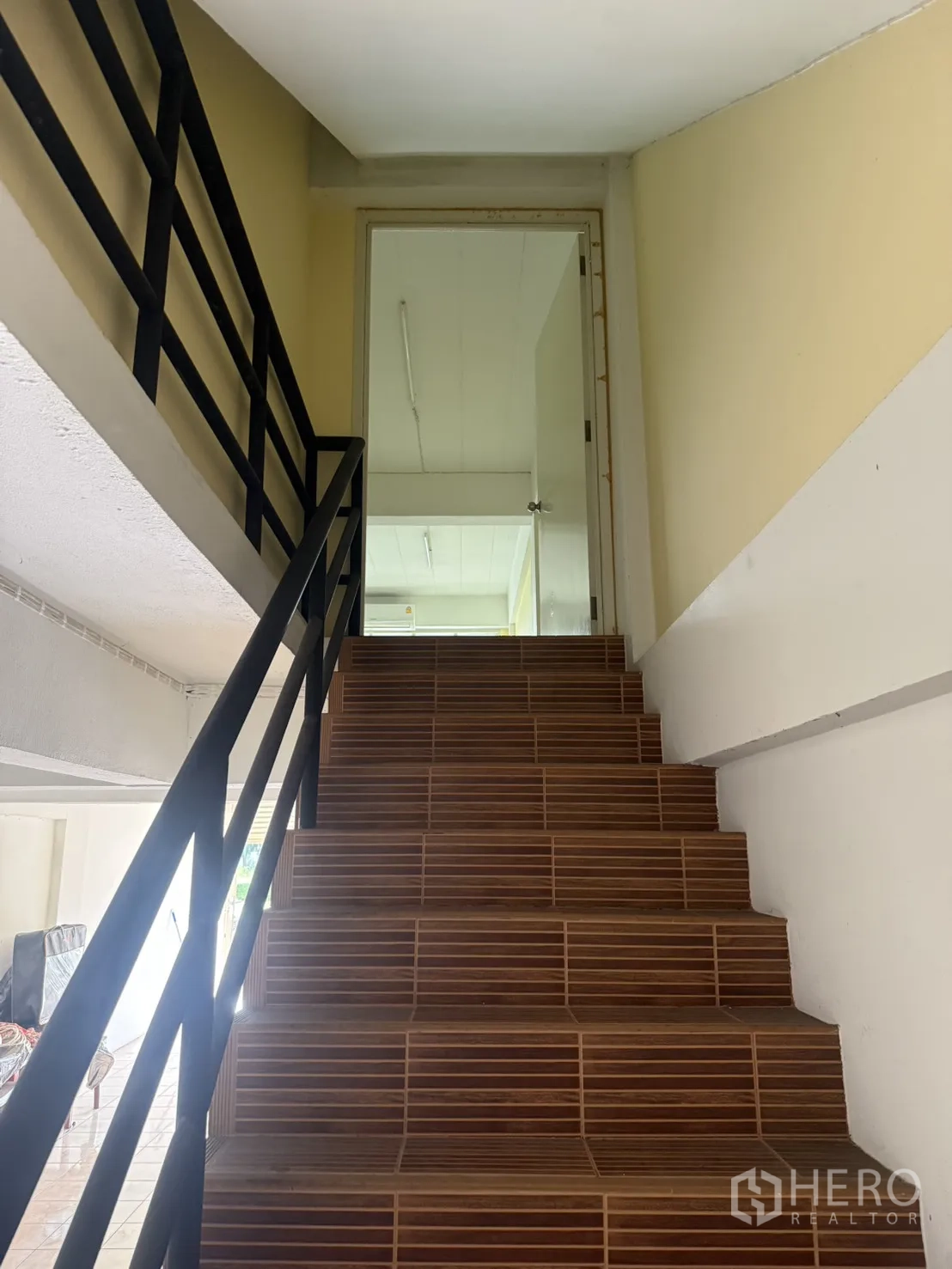 Shophouse for rent in Pak Kret, Nonthaburi - Brown-tiled staircase with black railing leading upstairs.