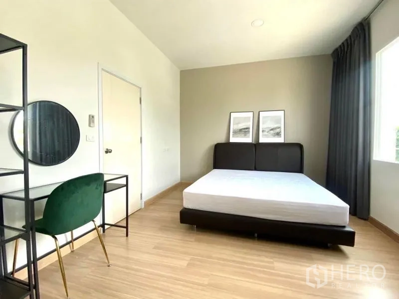 Townhouse for rent in Bang Phli, Samut Prakan - Minimalist bedroom with queen bed, desk, shelving unit and large window.