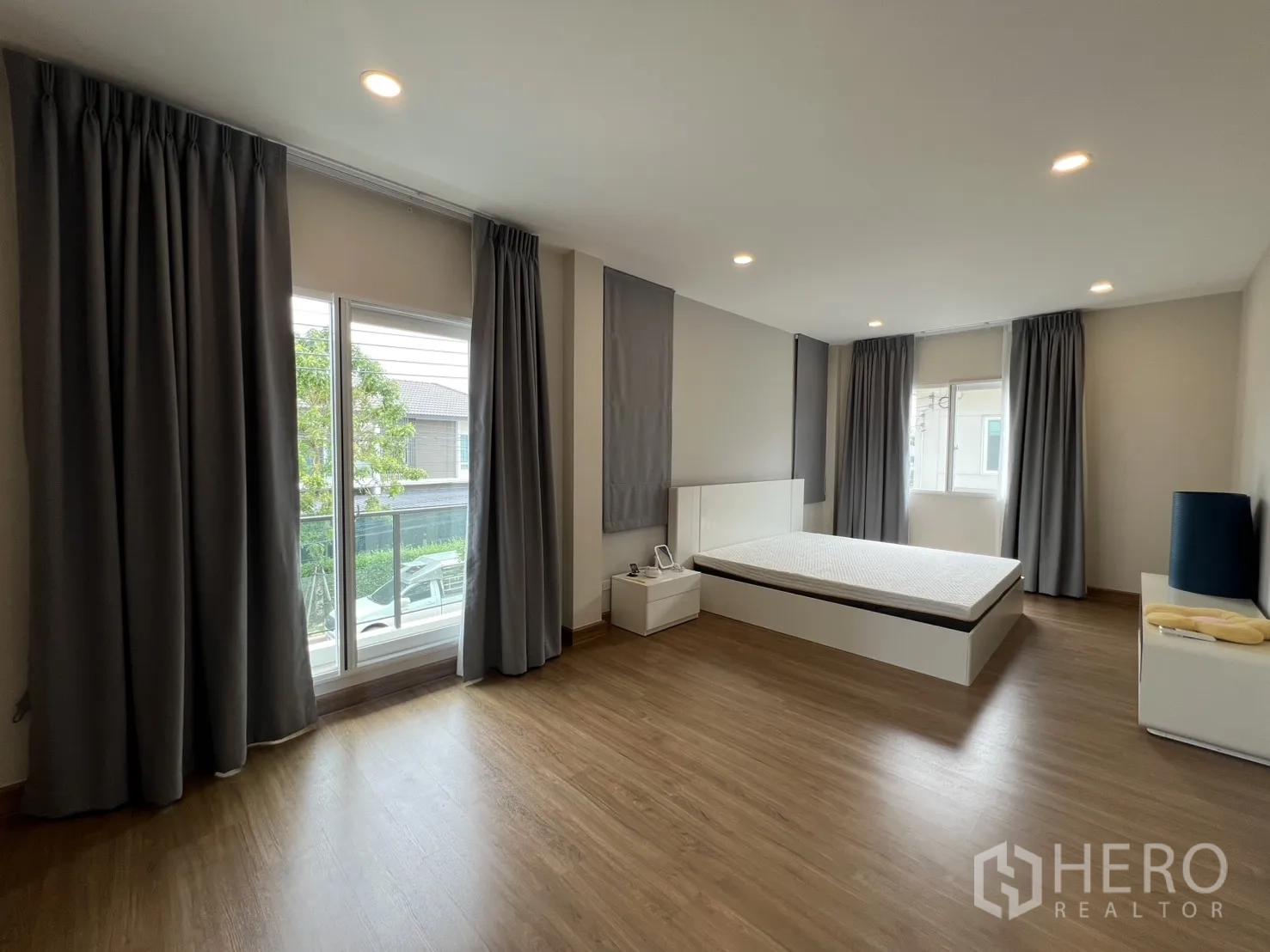 独栋房屋 for rent in Lat Krabang, Bangkok - 宽敞主卧设大窗、平台床、木地板与窗帘。