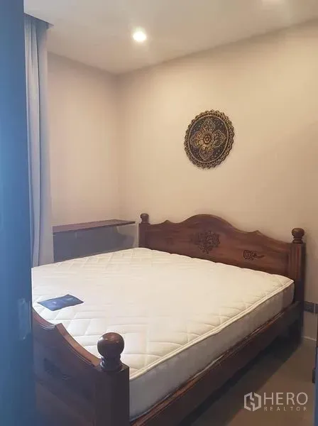 Condominium for rent in Watthana, Bangkok - Cozy bedroom with carved wooden bed frame and soft ceiling lighting.