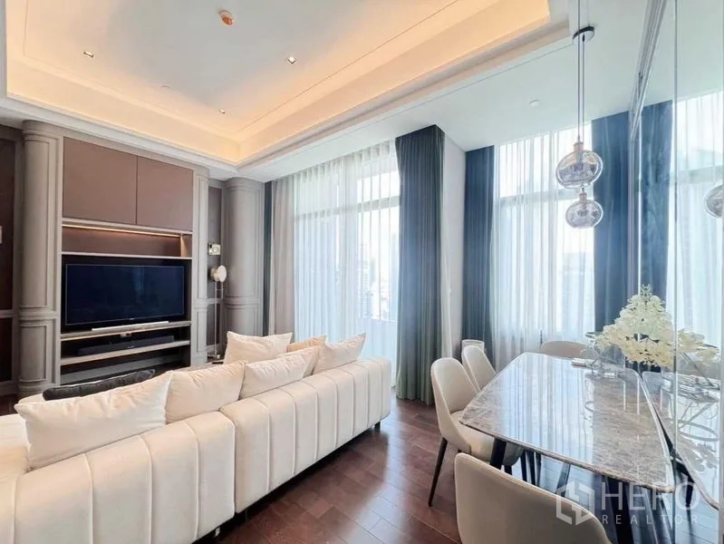 Condominium for rent in Watthana, Bangkok - Open-plan lounge and dining area with marble table, pendant lights and large curtains over dark wood floors.