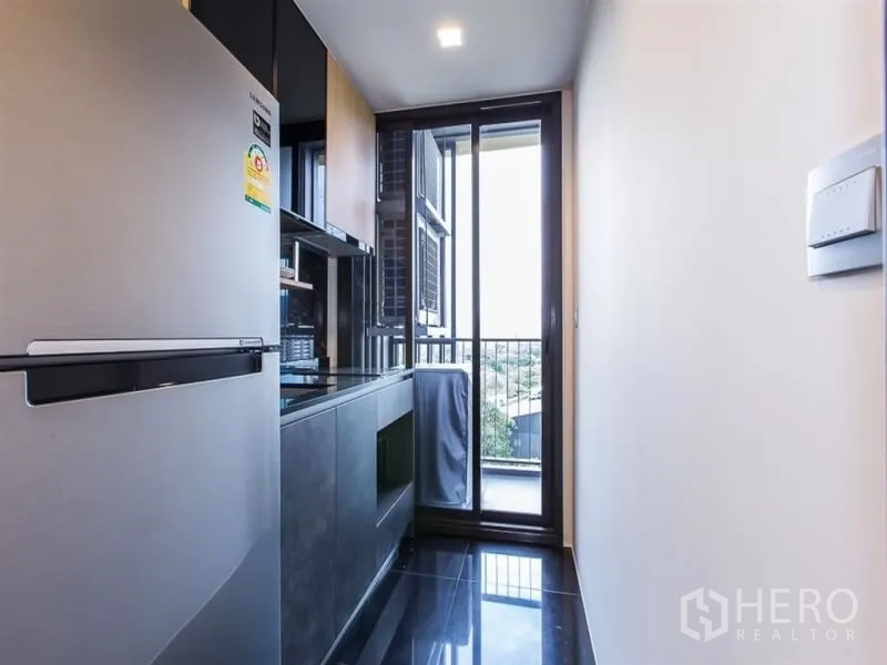 公寓 出租在Chatuchak, Bangkok - 狭长厨房，内置橱柜与大冰箱，通向阳台可观市景。