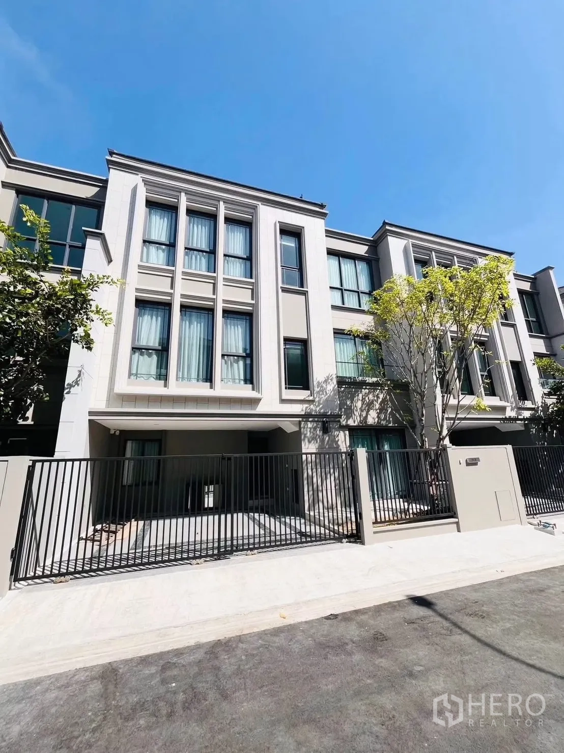 Townhouse for rent in Suan Luang, Bangkok - Contemporary townhouse exterior with tall windows and a gated driveway.