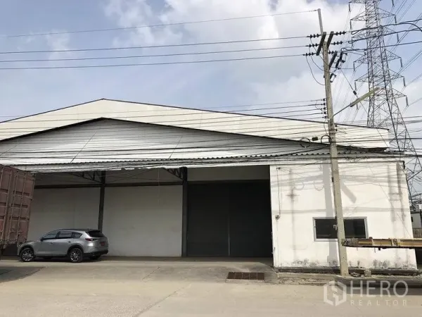 货栈 出租在Khlong Luang, Pathum Thani - 仓库外立面，宽大卷帘门、雨棚装卸区与卡车出入口