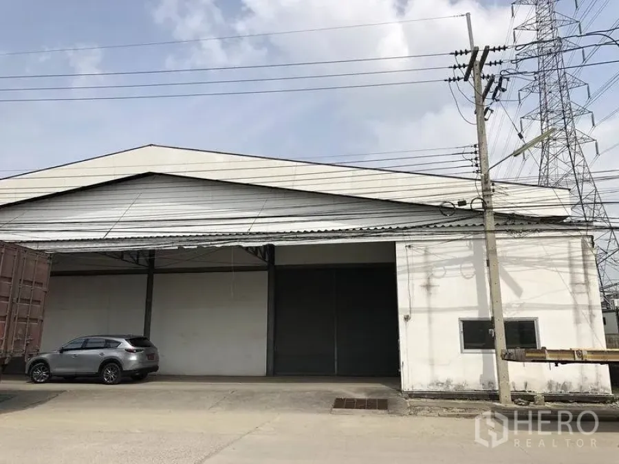 货栈 出租在Khlong Luang, Pathum Thani - 仓库外立面，宽大卷帘门、雨棚装卸区与卡车出入口