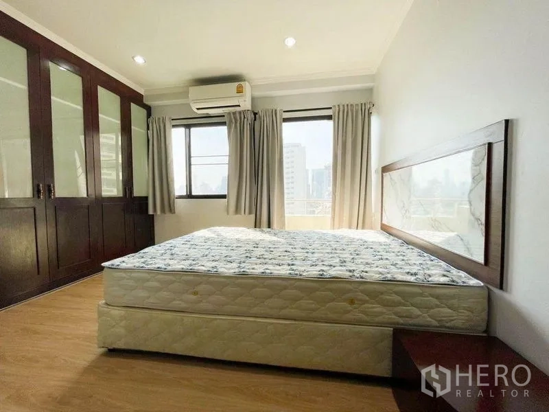 Condominium for rent or sale in Khlong Toei, Bangkok - Bright bedroom with large bed, built-in wardrobes and city-view windows.