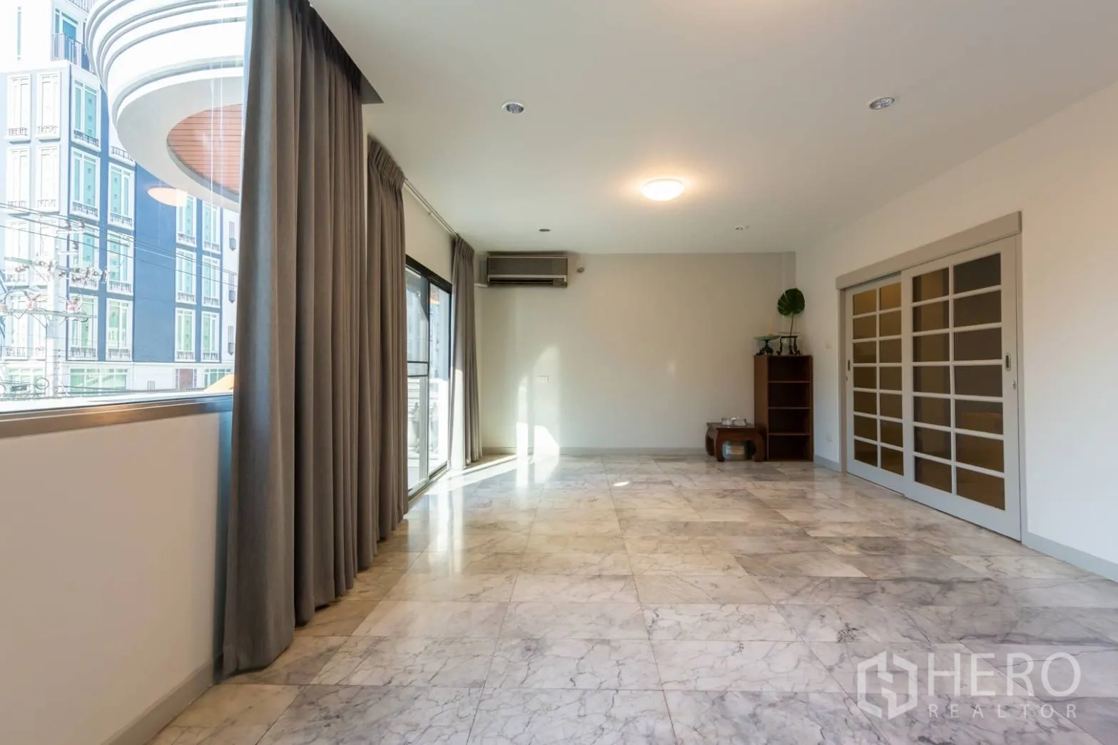 Home Office for rent in Bang Rak, Bangkok - Bright living area with large windows, marble floors and sliding doors to a balcony.
