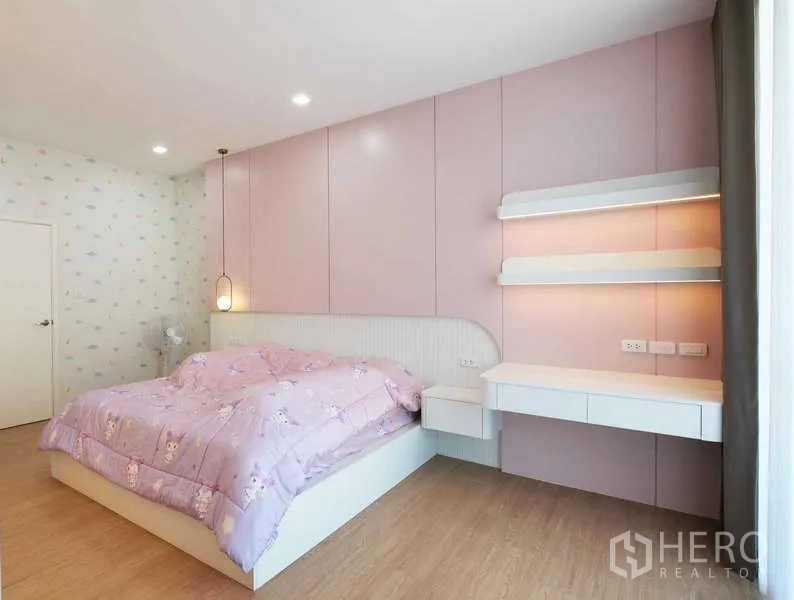 Detached House for rent or sale in Thanyaburi, Pathum Thani - Pastel-themed bedroom with pink paneled wall, built-in desk and large window.