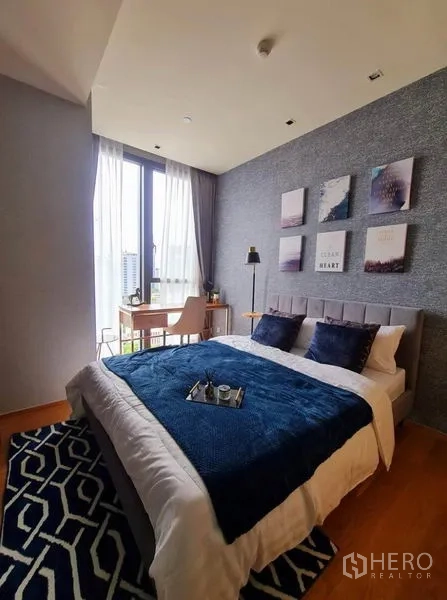 Condominium for rent in Khlong Toei, Bangkok - Cozy second bedroom with blue accents, artwork and desk by window.