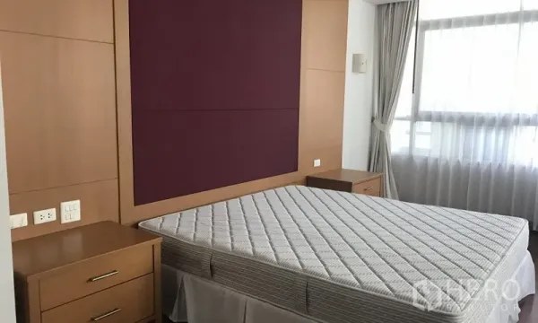 房间 出租在Watthana, Bangkok - 次卧配软包床头、双床头柜及带窗帘的窗户。