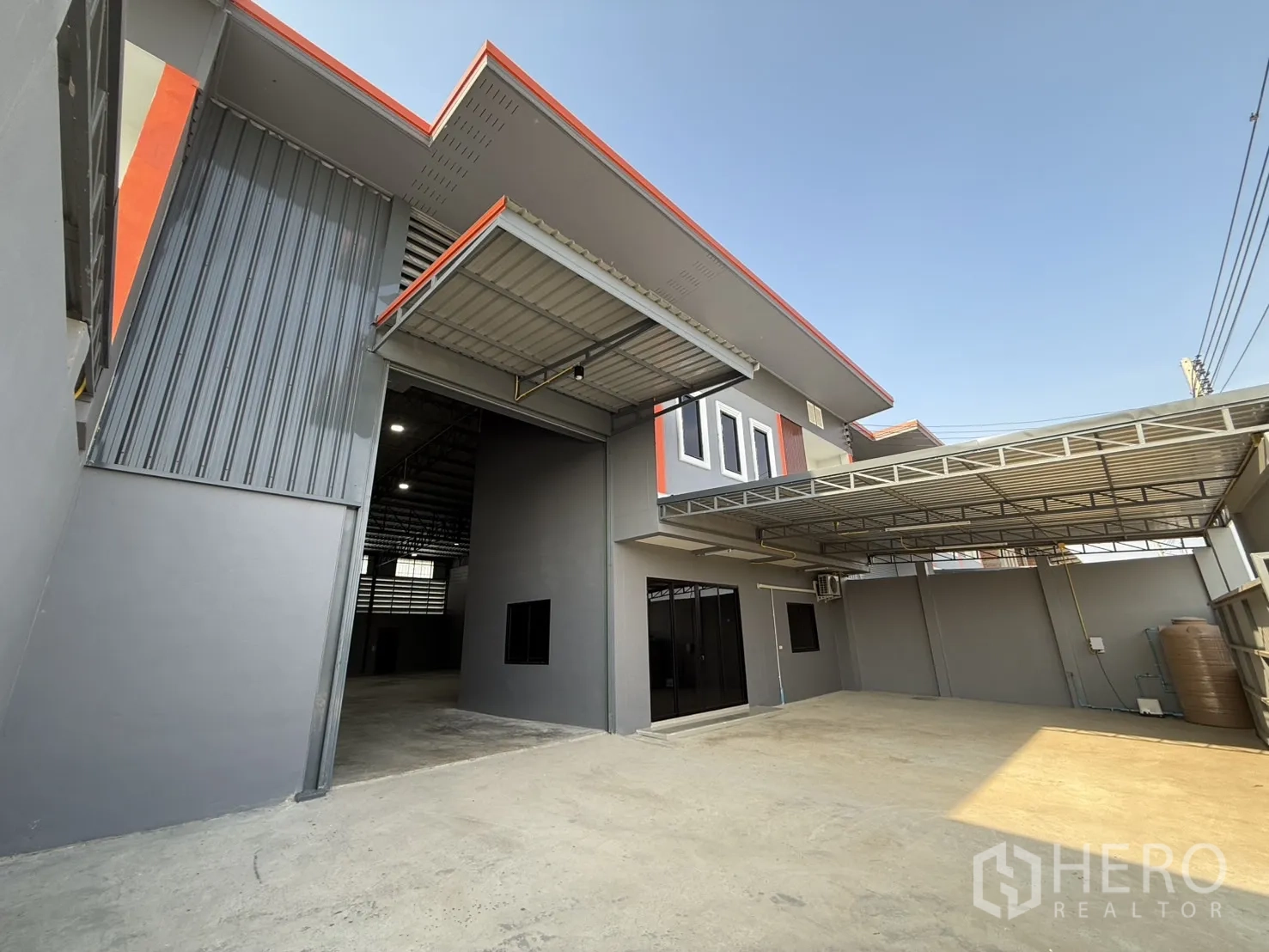 Warehouse for rent in Lam Luk Ka, Pathum Thani - Warehouse frontage with covered loading area and wide entrance.