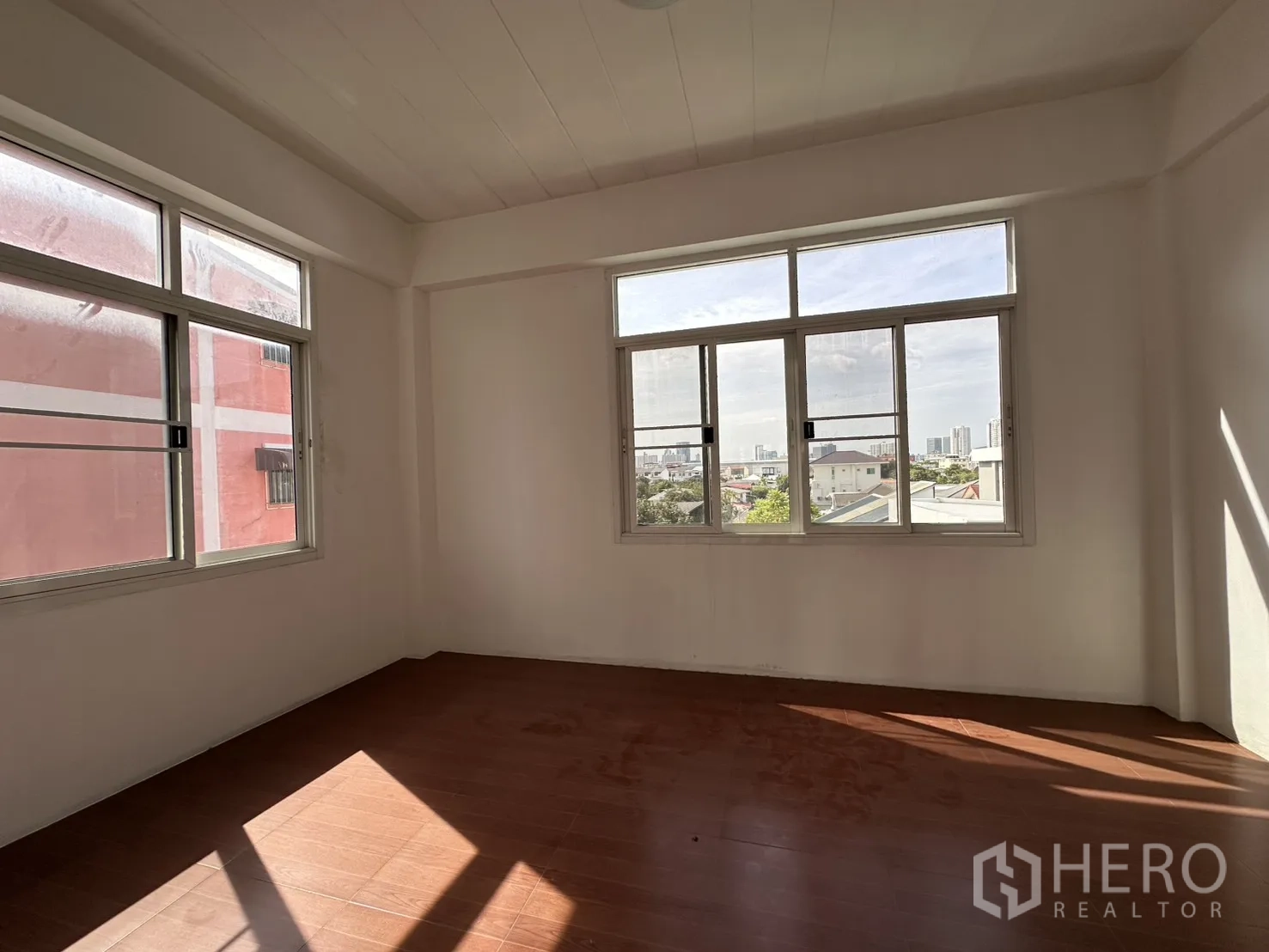 Shophouse for rent in Phra Khanong, Bangkok - Sunlit room with wide windows and city views.