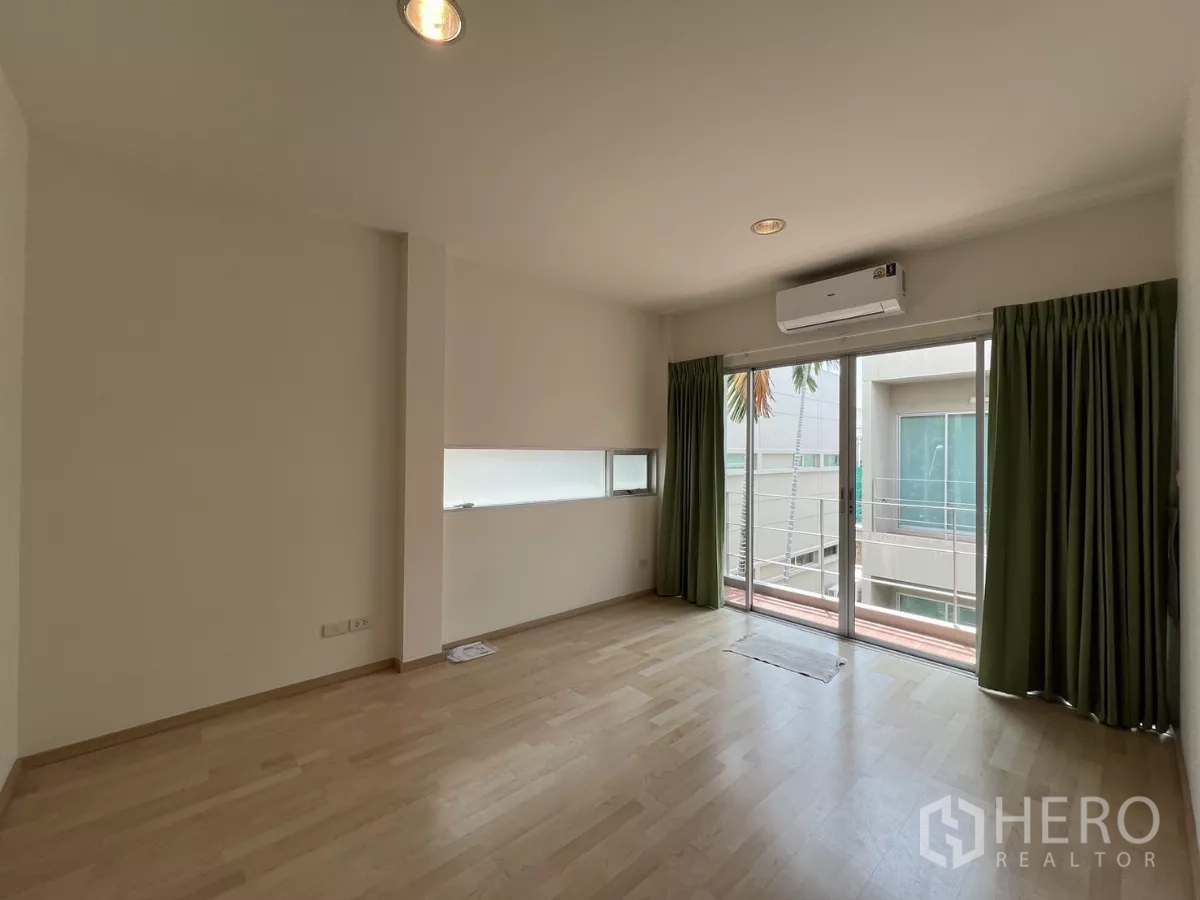 Townhouse for rent in Suan Luang, Bangkok - Upper-level room with wood flooring, balcony access, and air conditioning.