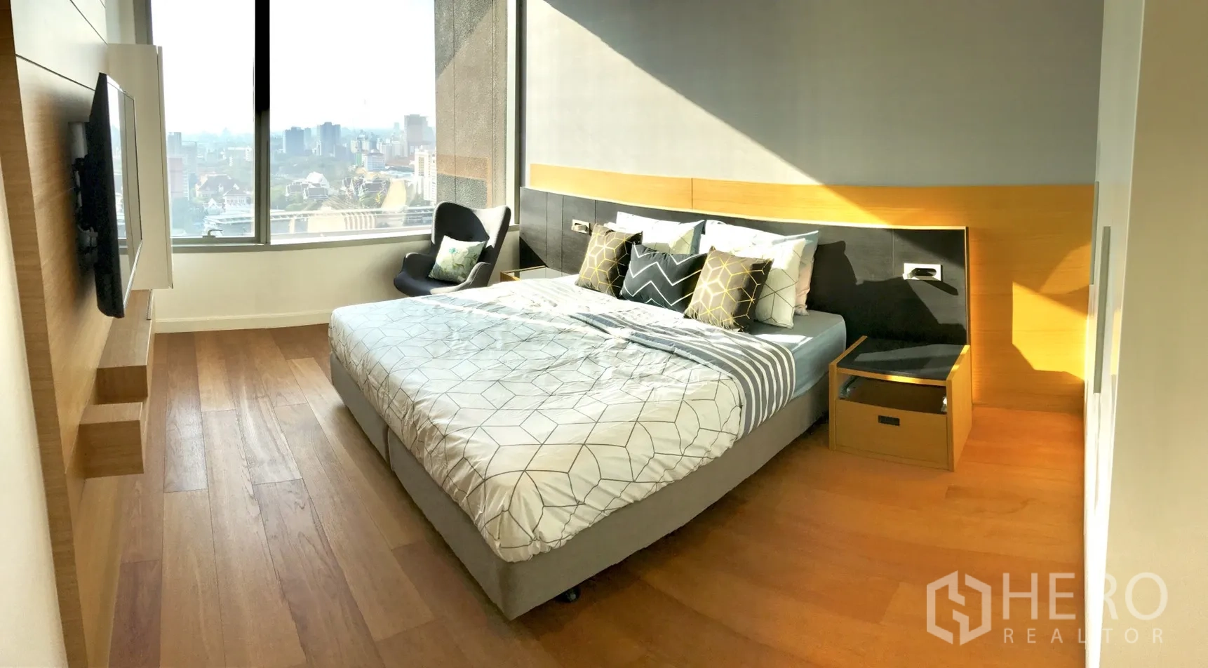 Condominium for rent in Pathum Wan, Bangkok - Sunlit bedroom with large window, wood floors and expansive city view.