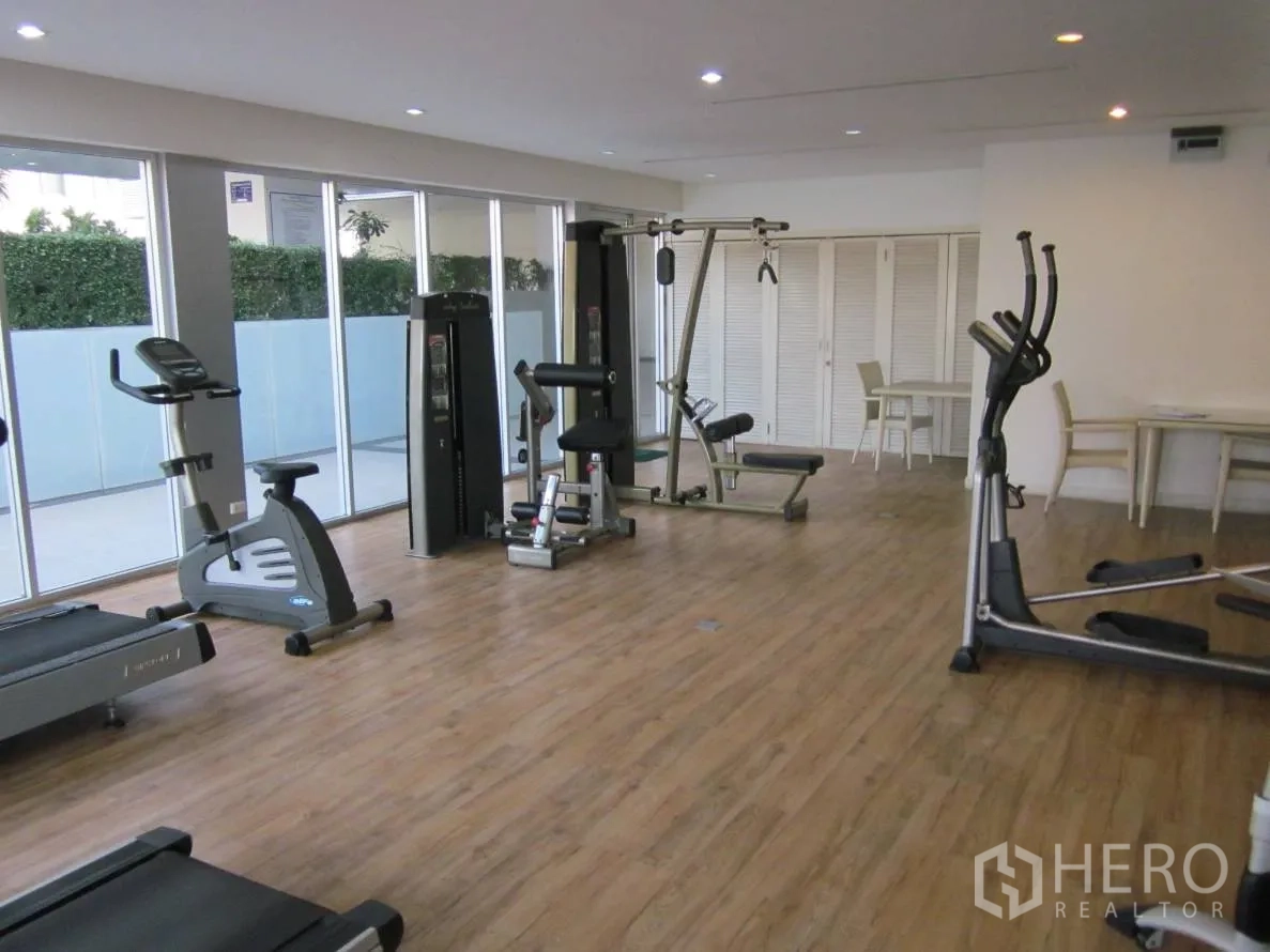 Condominium for rent or sale in Khlong Toei, Bangkok - Well-equipped fitness room with treadmills, bikes, weight machines and floor-to-ceiling windows.