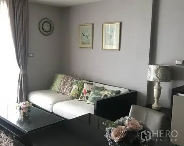 公寓 出租在Watthana, Bangkok - 明亮客厅，白色沙发、玻璃茶几与窗帘，位于BTS Ekkamai附近的现代公寓。