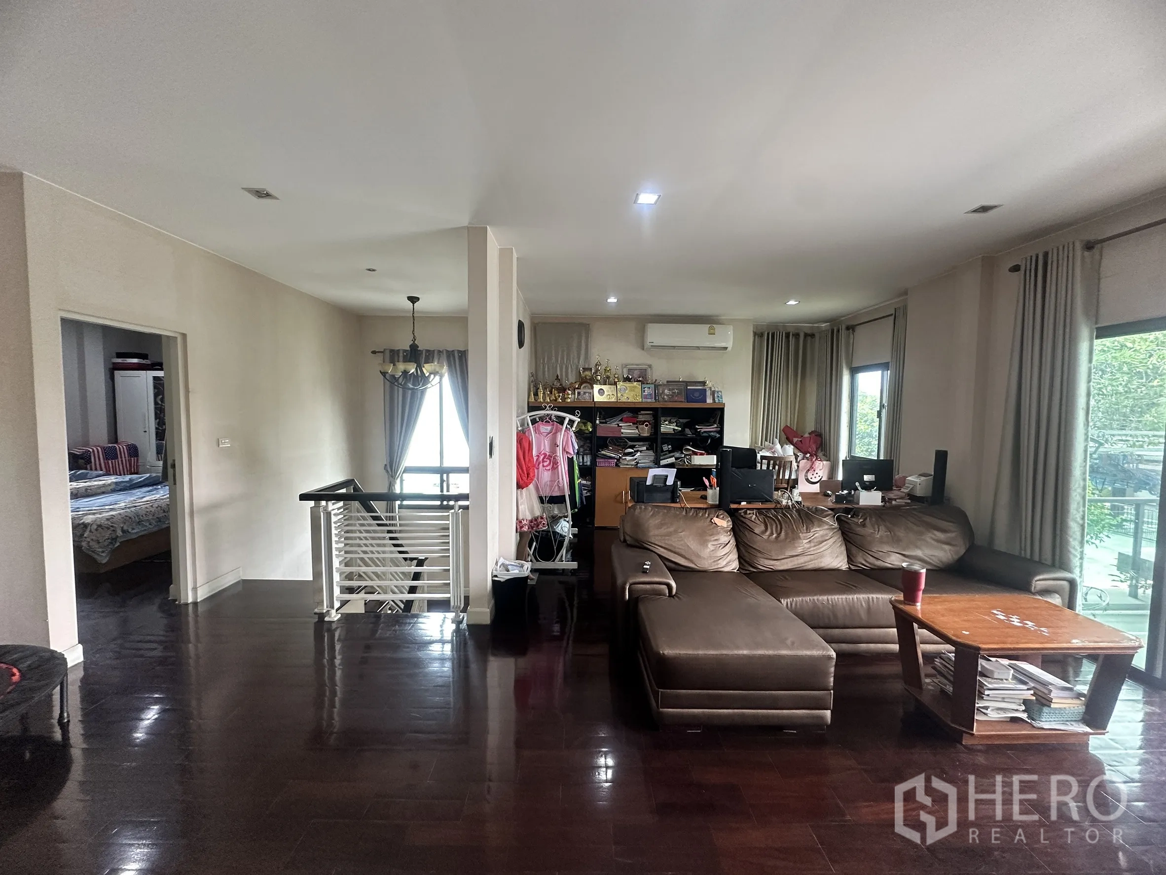 独栋房屋 for sale in Pak Kret, Nonthaburi - 二楼起居区，L形沙发、窗户与楼梯扶手。
