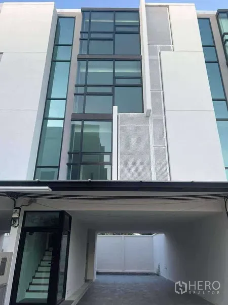 带办公室的家 出租在Bang Khen, Bangkok - 一层入口带玻璃门，建筑下方设有遮蔽停车位。