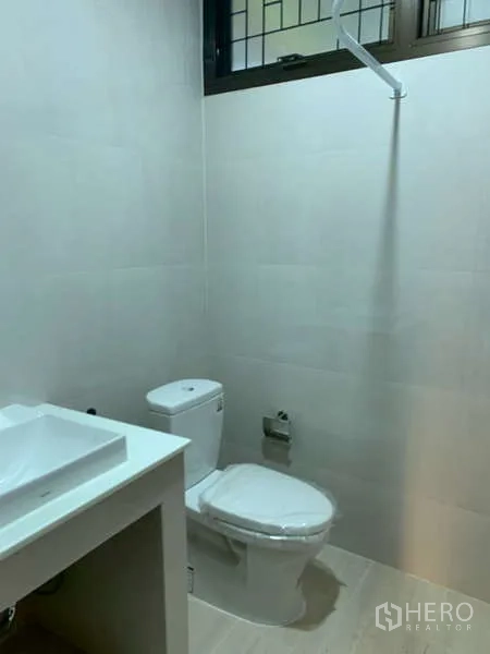 独立式住宅 出租或出售在Phra Khanong, Bangkok - 翻新浴室，白色瓷砖、台盆和马桶，窗下采光。
