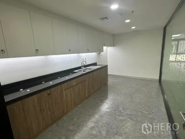 办公空间 出租在Khlong Toei, Bangkok - 配备长台面与水槽的办公室茶水间，上方设吊顶灯与壁柜。
