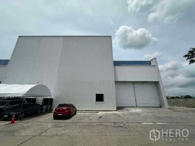 Factory for rent in Khlong Luang, Pathum Thani - Front facade of the warehouse with canopy parking and dual loading doors.