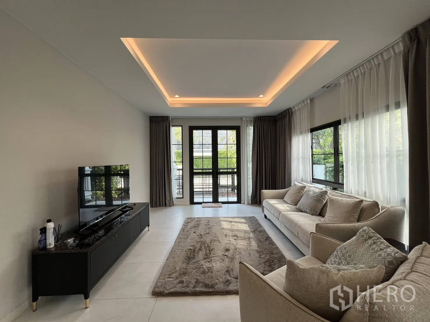 独栋房屋 for rent in Bang Phli, Samut Prakan - 客厅配电视柜、两张沙发和通向露台的门。