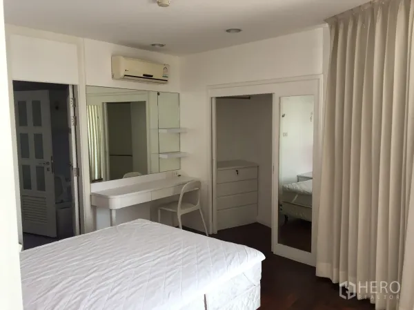 公寓 出租在Watthana, Bangkok - 卧室带梳妆台、镜面衣柜与整面窗帘。