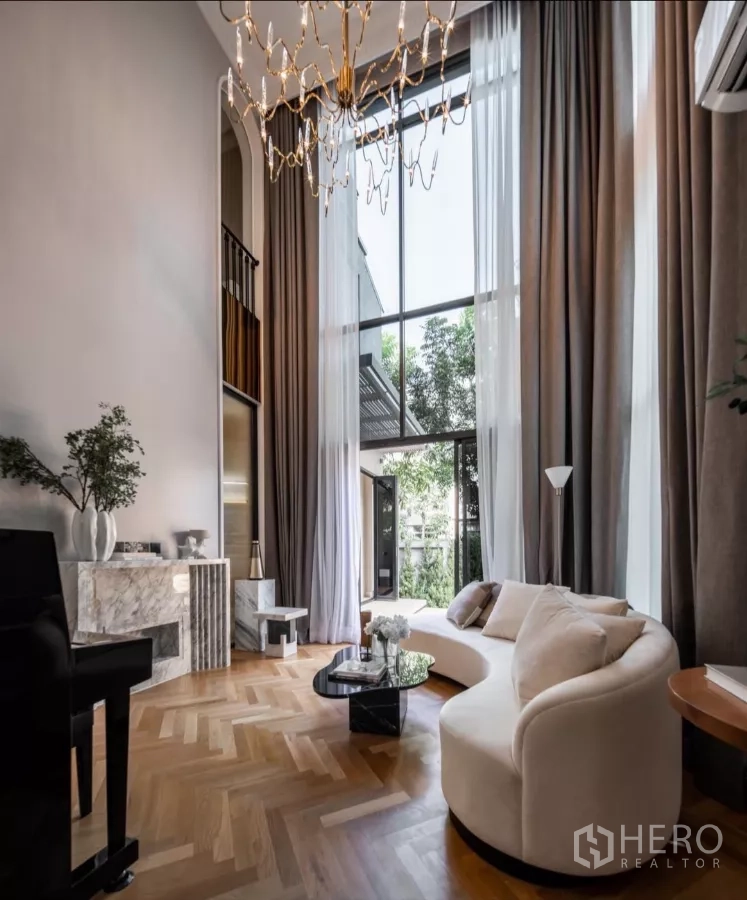 Detached House for rent or sale in Phra Khanong, Bangkok - Double-volume living room with 6.7 m ceiling, chandelier, full-height drapes and large windows.