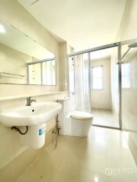 Townhouse for rent in Prawet, Bangkok - Clean bathroom with glass-enclosed shower, wide mirror and white sanitary ware.