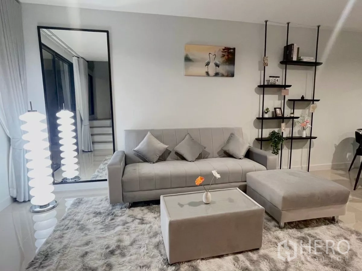 Townhouse for rent in Samut Prakan - Cozy lounge with grey sofa, ottoman, shag rug and designer floor lamps.